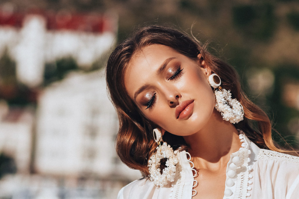 lady with rustic color make up and a white outfit with huge white earrings