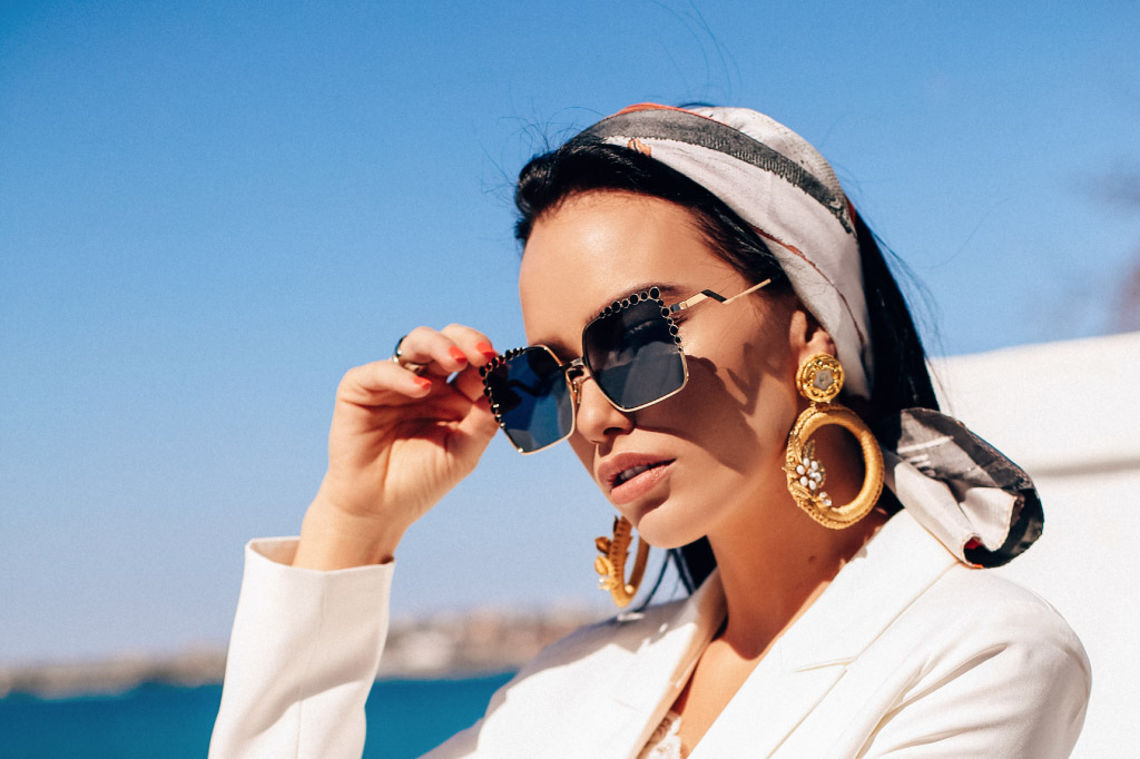 lady on a vacation with gold sunglasses, huge earrings and ring