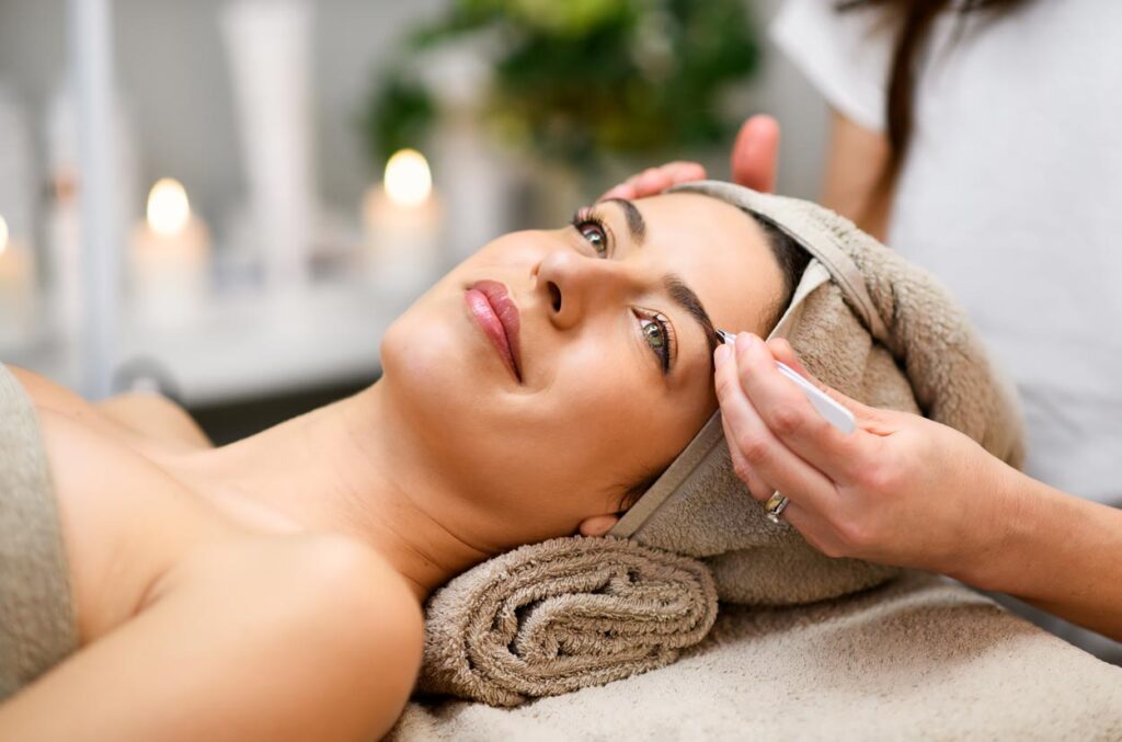 woman relaxing while having her eyebrows tweezed