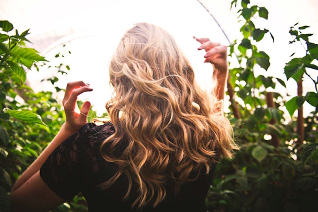 beautiful long blonde flowing hair surrounded by leaves in nature