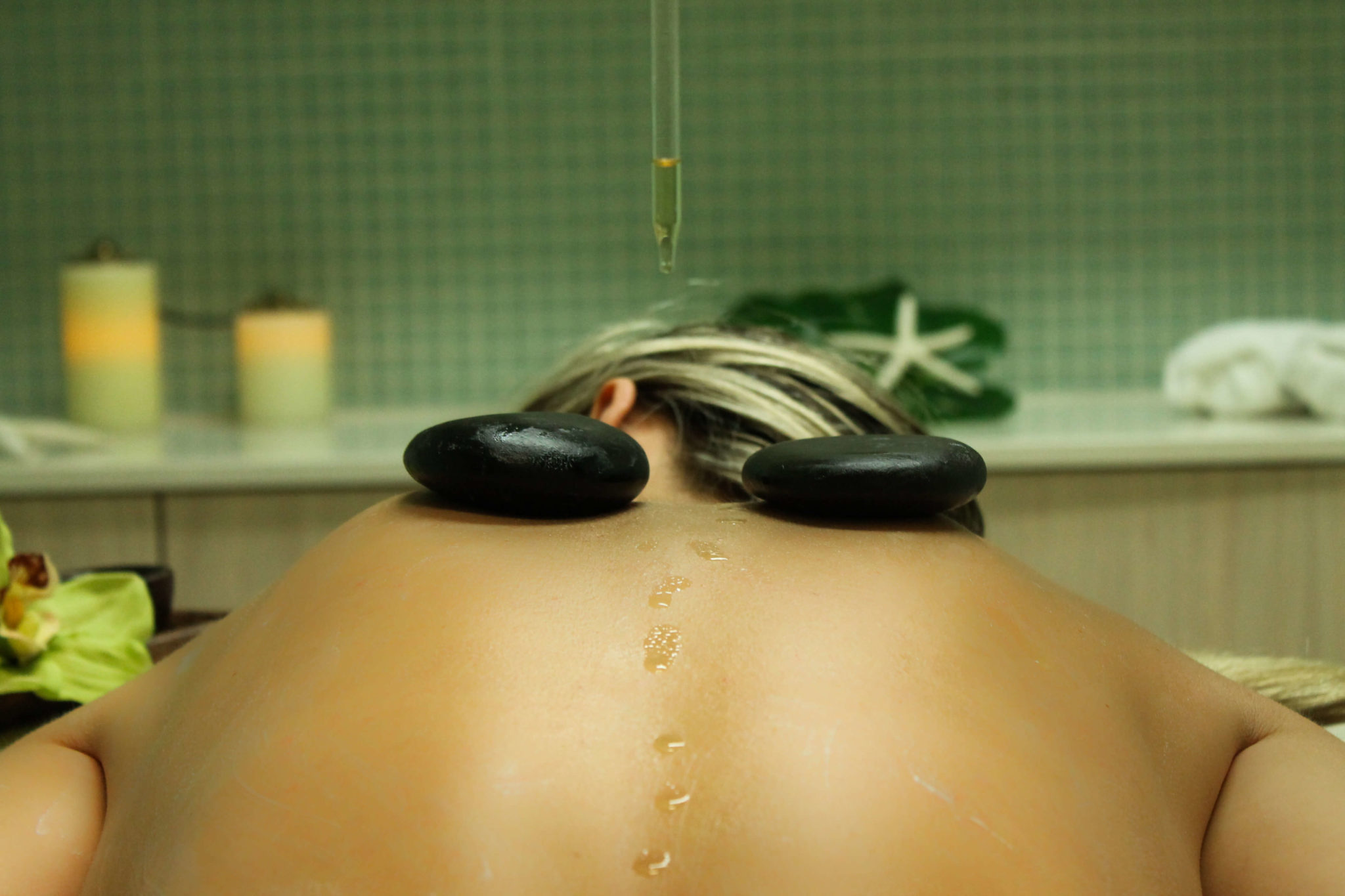 serum dripping in woman's back, with two lava stones on top of her