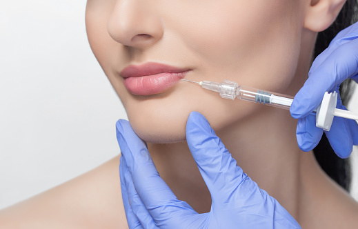 The doctor cosmetologist makes Lip augmentation procedure of a beautiful woman in a beauty salon.Cosmetology skin care.