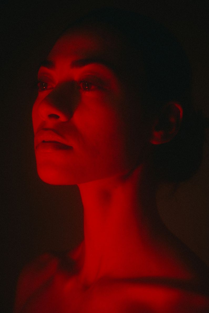 A women dimly illuminated with red light in a dark space