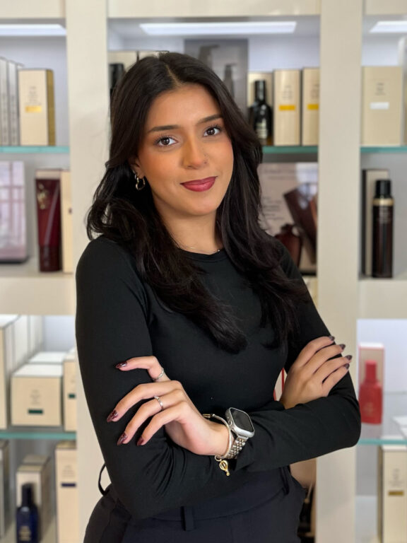 Nicole Hair Colorist stands in front of a retail counter at Anushka Spa, Salon & Cosmedical Centre in West Palm Beach, Florida.